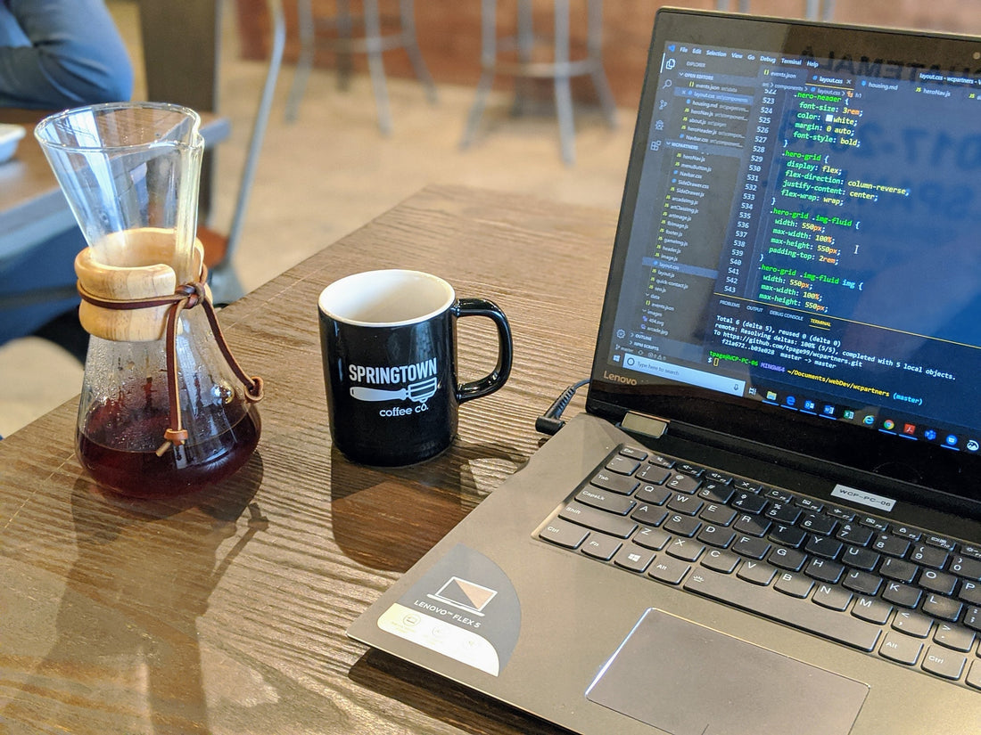 coffee mug with springtown coffee logo next to a small chemex and laptop open with code on screen