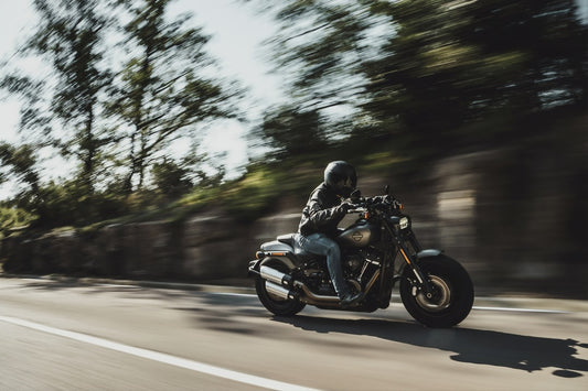 motorcycle rider wearing a helmet driving at a fast rate of speed