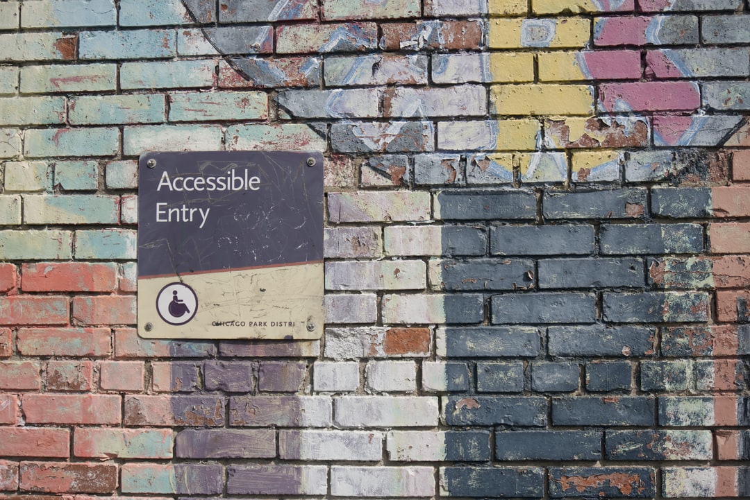 faded accessibility sign on brick wall with text on sign that reads accessible entry