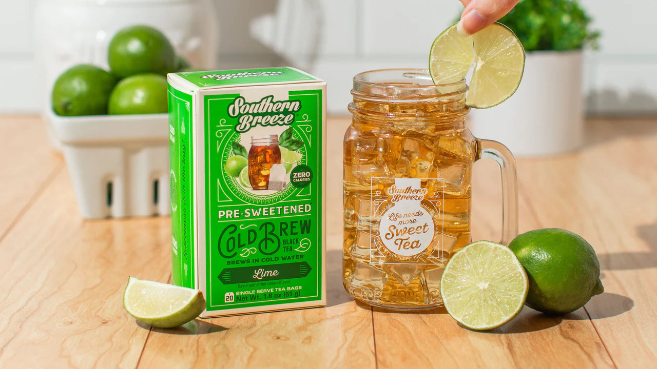 Southern Breeze pre-sweetened cold brew tea packaging with a glass of tea and lime slices on a wooden table.