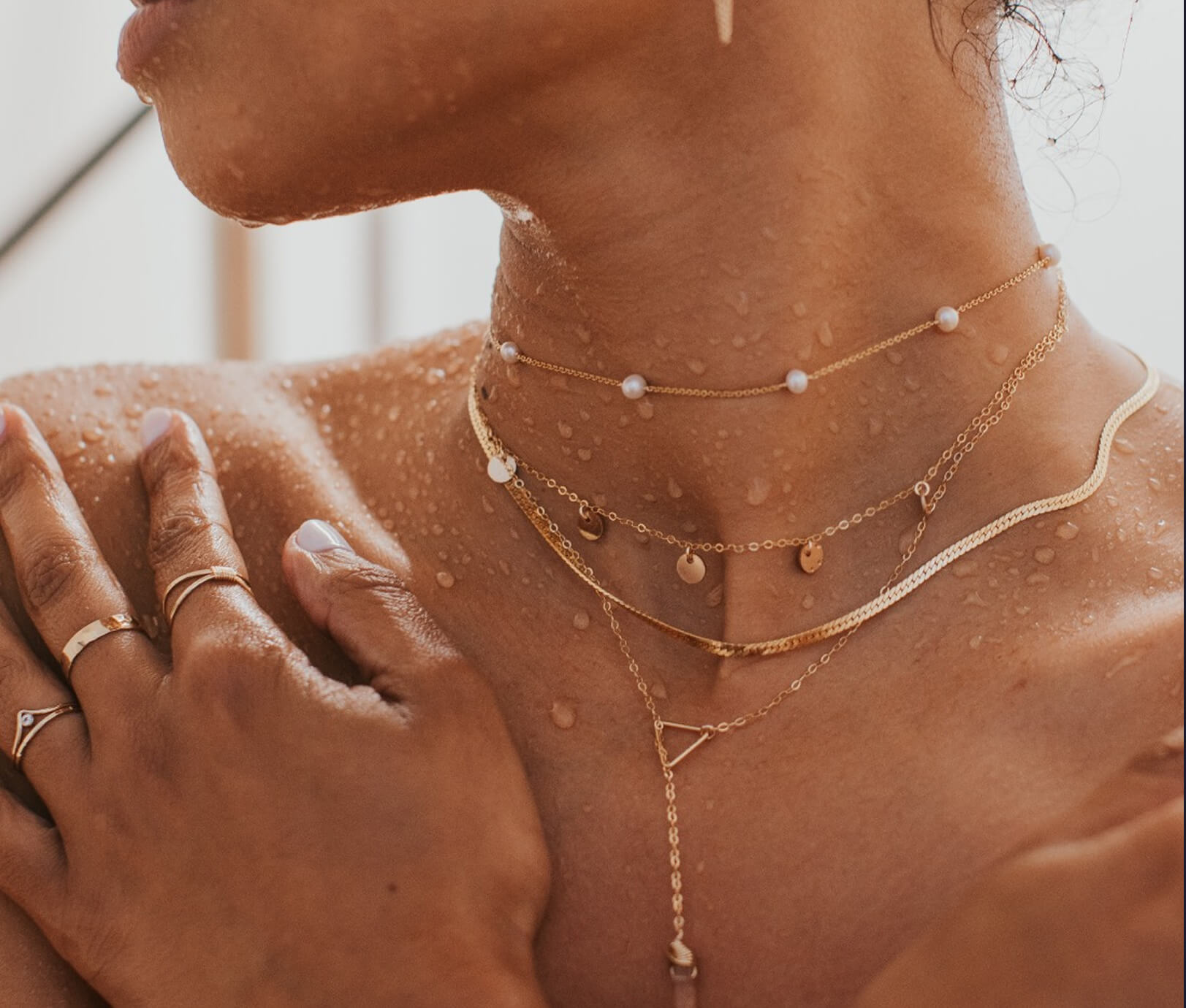 Close-up of a person wearing multiple gold necklaces with small beads.